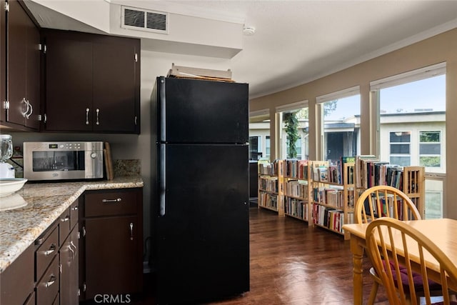 kitchen featuring dark brown cabinets, dark wood-type flooring, crown molding, and black refrigerator