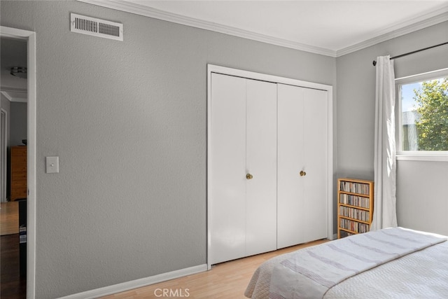 bedroom with a closet, light wood-type flooring, and ornamental molding