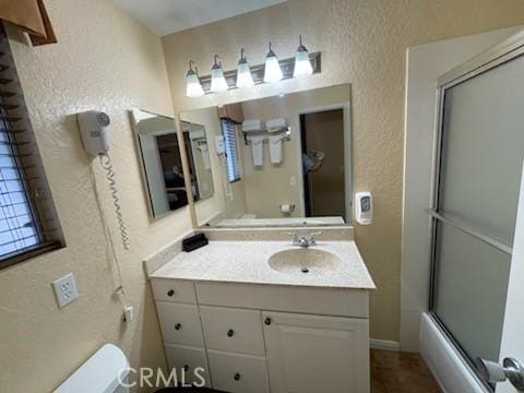 full bathroom featuring vanity, toilet, and bath / shower combo with glass door