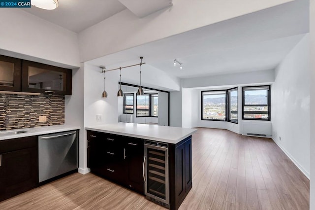 kitchen with kitchen peninsula, stainless steel dishwasher, beverage cooler, light wood-type flooring, and decorative backsplash