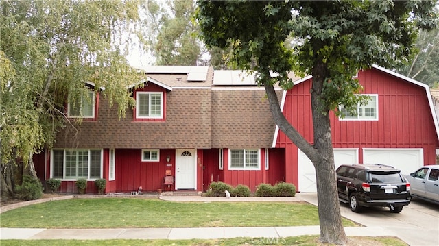 view of front of home featuring a garage, solar panels, and a front yard