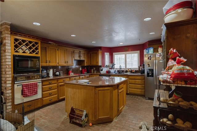 kitchen with wall oven, stainless steel fridge, sink, a kitchen island, and black microwave