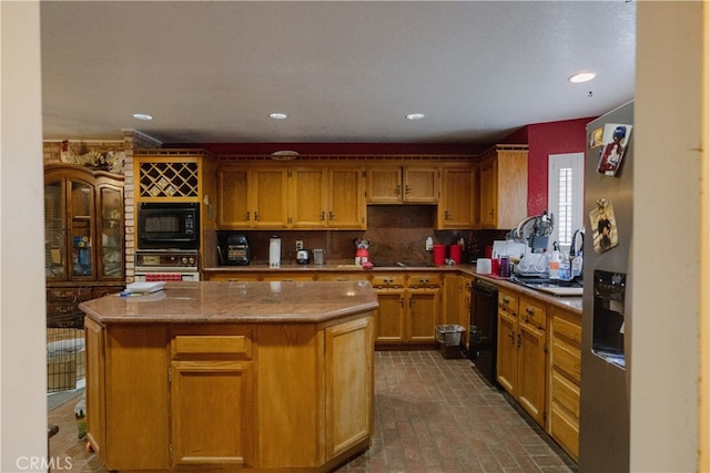 kitchen with backsplash, black appliances, a kitchen island, and sink