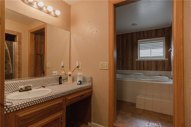 bathroom featuring vanity, tiled bath, tile patterned flooring, and tasteful backsplash