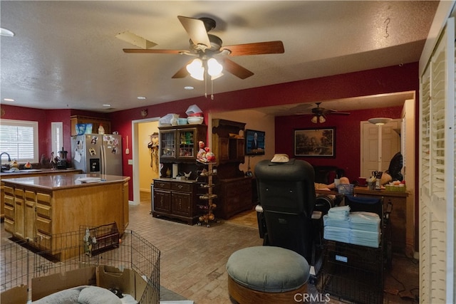 interior space featuring a center island, ceiling fan, light hardwood / wood-style flooring, stainless steel refrigerator with ice dispenser, and sink