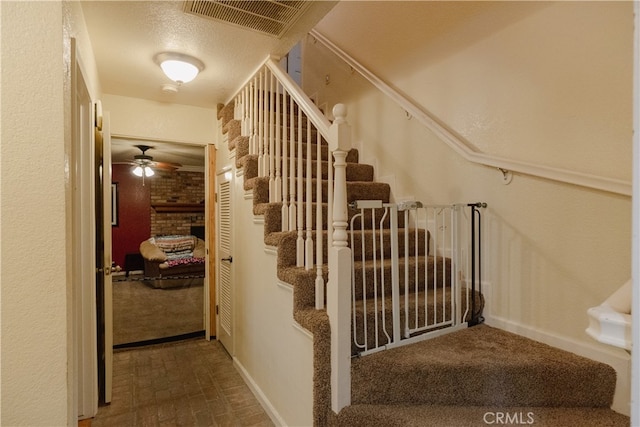 stairway with a textured ceiling and ceiling fan