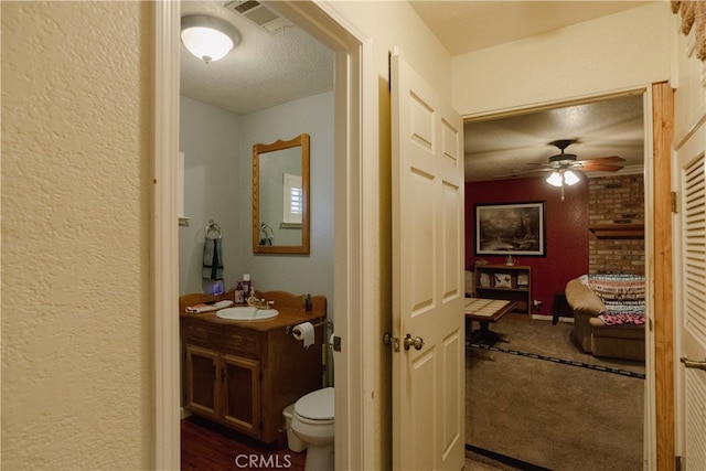 bathroom featuring ceiling fan, vanity, toilet, and a textured ceiling