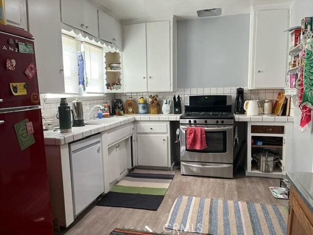 kitchen featuring stainless steel gas range, dishwasher, tile counters, white cabinetry, and fridge