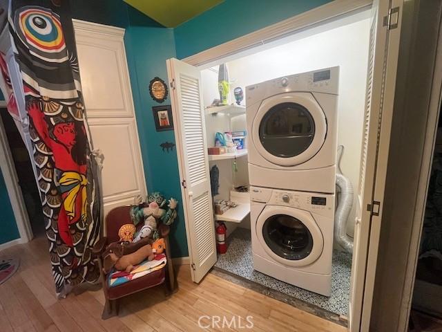 laundry area featuring light wood-type flooring and stacked washer / drying machine