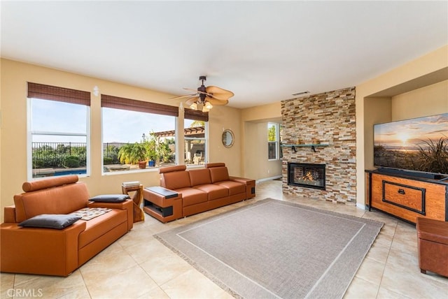 tiled living room featuring a stone fireplace and ceiling fan