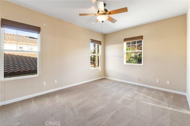 empty room with a wealth of natural light, carpet floors, and ceiling fan