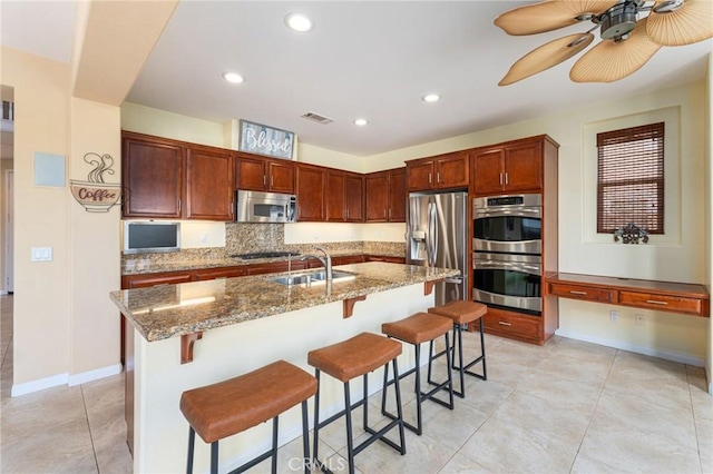 kitchen featuring a center island with sink, a breakfast bar, sink, and stainless steel appliances