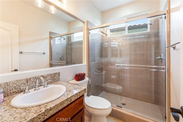 bathroom with a wealth of natural light, vanity, a shower with shower door, and toilet