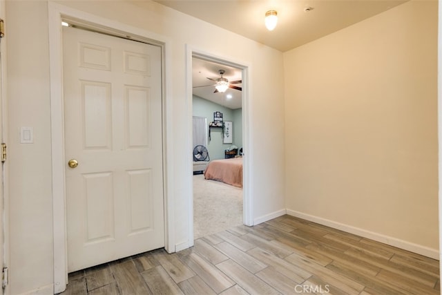 hall featuring lofted ceiling and light hardwood / wood-style flooring