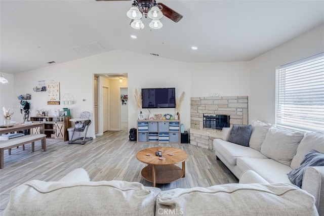 living room featuring a fireplace, vaulted ceiling, ceiling fan, and light hardwood / wood-style flooring