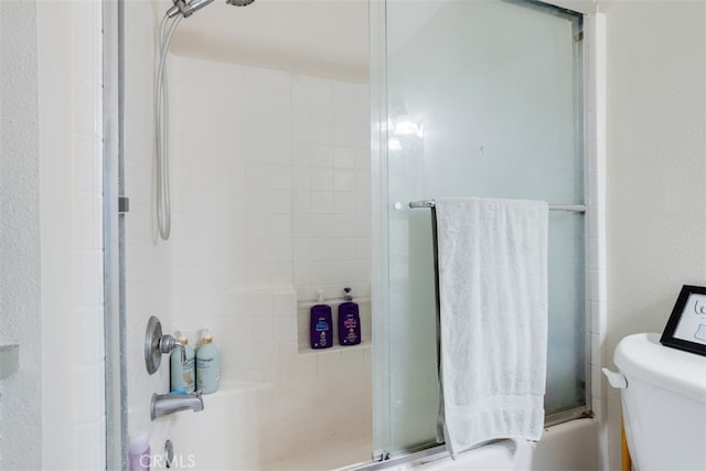 bathroom featuring combined bath / shower with glass door and toilet