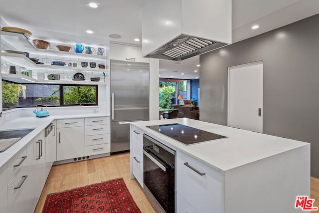 kitchen featuring black appliances, light hardwood / wood-style floors, white cabinetry, and premium range hood