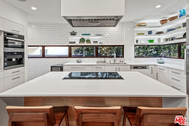 kitchen with decorative backsplash, a kitchen breakfast bar, and white cabinets