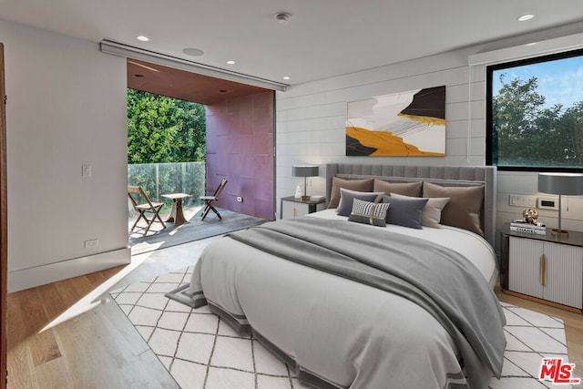 bedroom featuring access to outside, multiple windows, and light hardwood / wood-style flooring