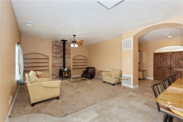 living room featuring ceiling fan and a wood stove