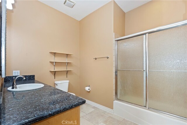 full bathroom featuring shower / bath combination with glass door, vanity, tile patterned flooring, and toilet