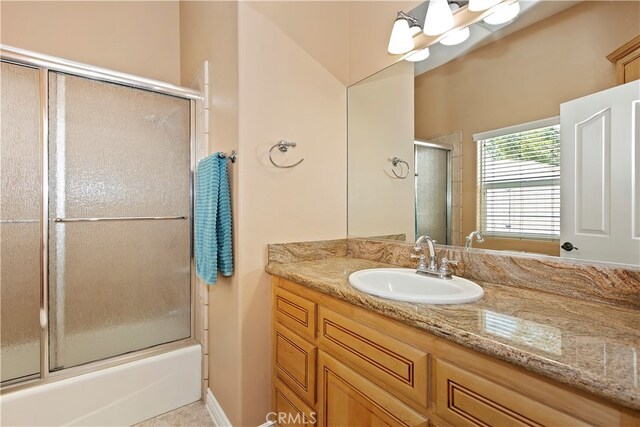 bathroom featuring shower / bath combination with glass door and vanity