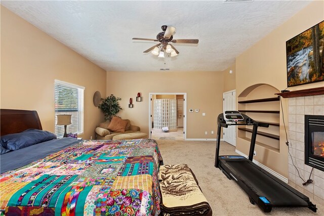 carpeted bedroom featuring a textured ceiling, a tile fireplace, and ceiling fan