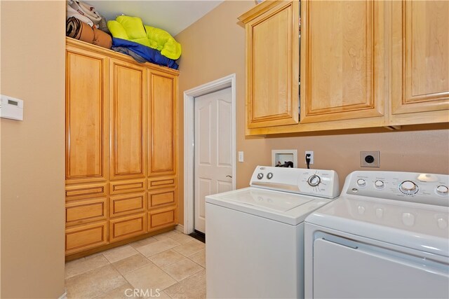 clothes washing area featuring cabinets, light tile patterned flooring, and washing machine and dryer