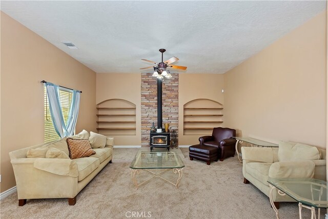 carpeted living room with ceiling fan, a textured ceiling, and a wood stove