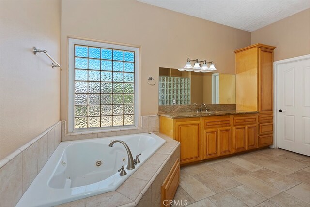 bathroom featuring a textured ceiling, tiled bath, and vanity