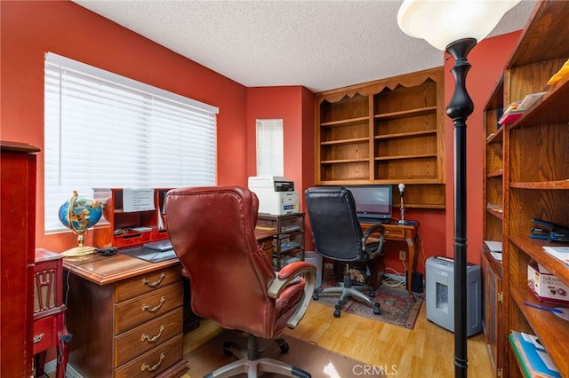 office featuring light wood-type flooring and a textured ceiling