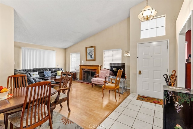 dining area with a brick fireplace, vaulted ceiling, and light tile patterned floors