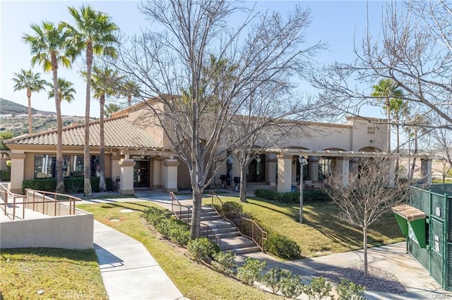 exterior space with a tile roof, fence, a front lawn, and stucco siding