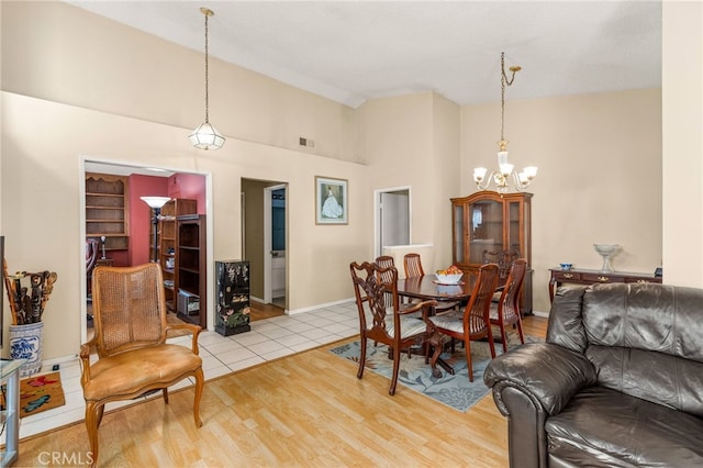 dining area featuring high vaulted ceiling, a notable chandelier, visible vents, baseboards, and light wood-style floors