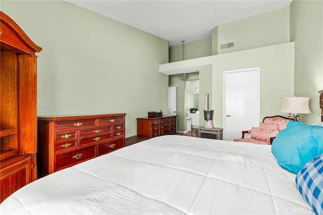 bedroom featuring visible vents, a textured ceiling, and a high ceiling