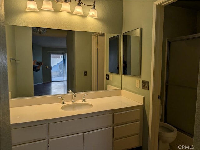 full bath featuring vanity, toilet, and a shower with door