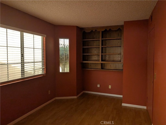 spare room with a textured ceiling, baseboards, and wood finished floors