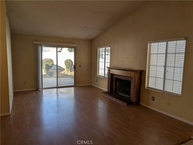 unfurnished living room with lofted ceiling, a brick fireplace, baseboards, and wood finished floors