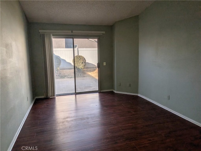 unfurnished room with a textured ceiling, dark wood-type flooring, and baseboards