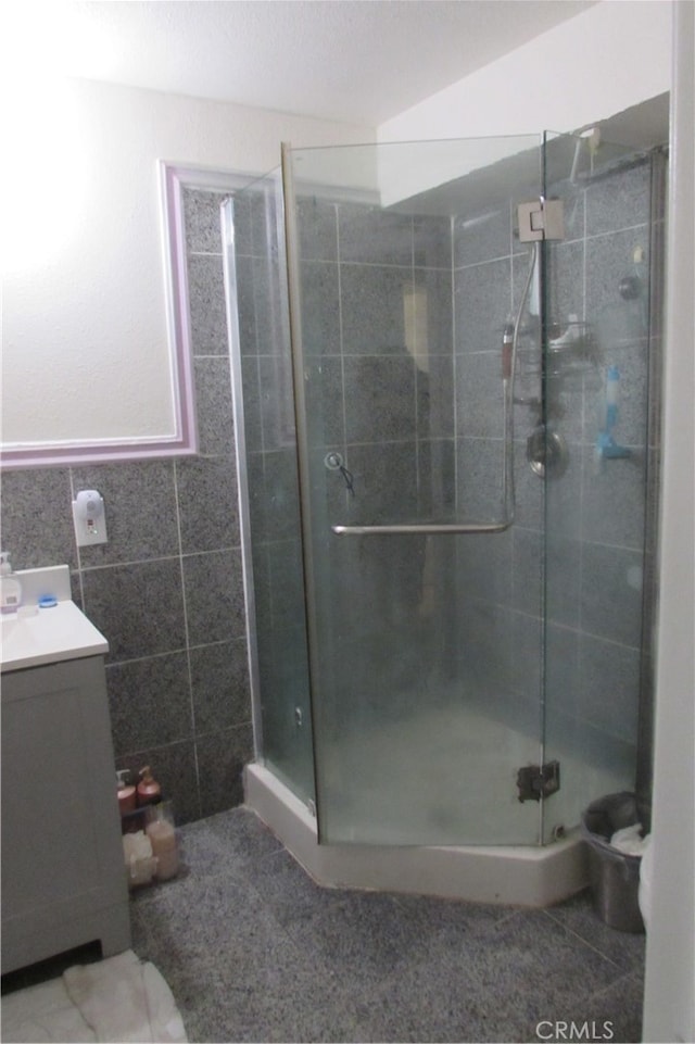 bathroom with tile walls, vanity, and a shower with door