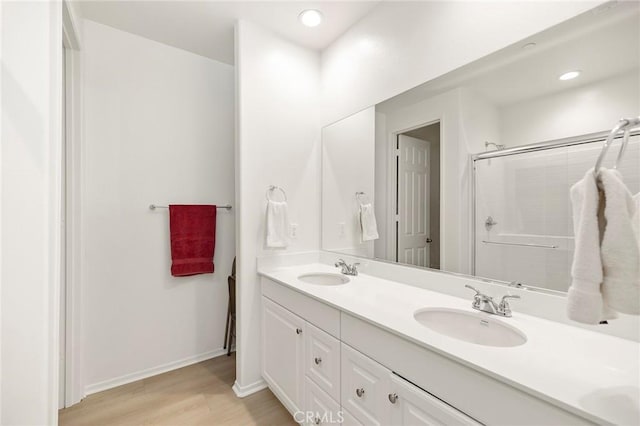 bathroom with hardwood / wood-style flooring, vanity, and an enclosed shower