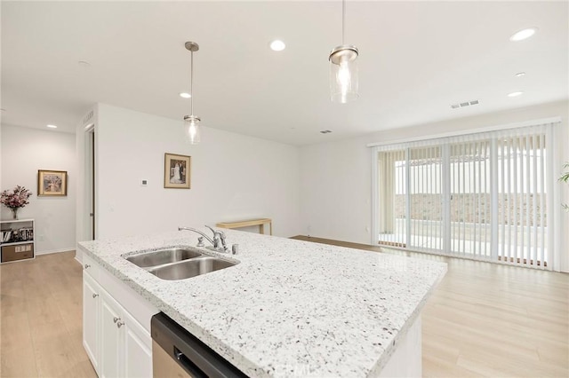 kitchen with light wood-type flooring, sink, decorative light fixtures, a center island with sink, and white cabinets