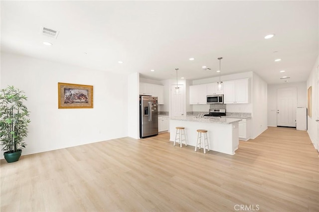 kitchen featuring stainless steel appliances, light hardwood / wood-style floors, a kitchen island with sink, a breakfast bar, and white cabinets