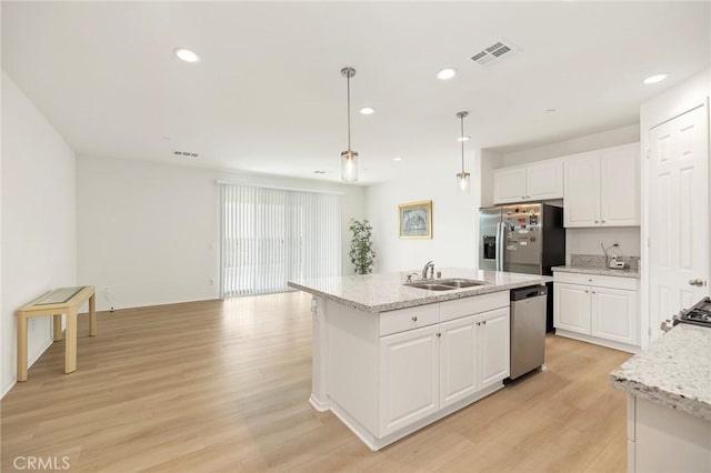 kitchen featuring white cabinets, appliances with stainless steel finishes, light wood-type flooring, and decorative light fixtures