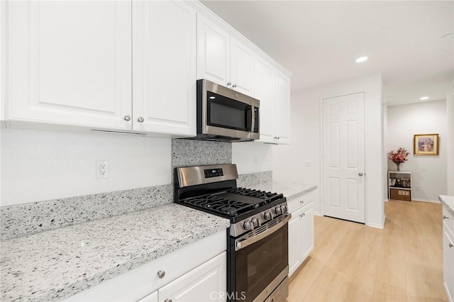 kitchen featuring white cabinetry, light hardwood / wood-style floors, light stone counters, and appliances with stainless steel finishes