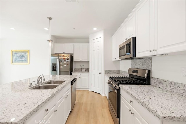 kitchen with white cabinets, pendant lighting, stainless steel appliances, and sink