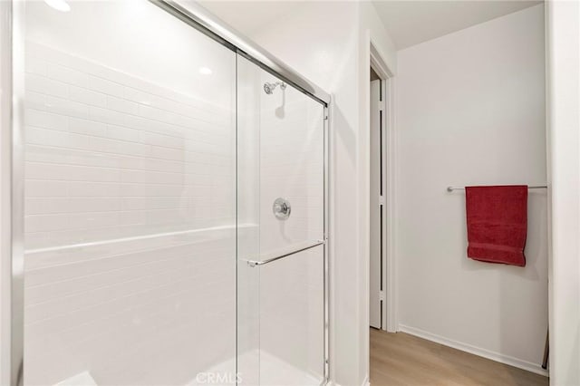 bathroom with wood-type flooring and a shower with door