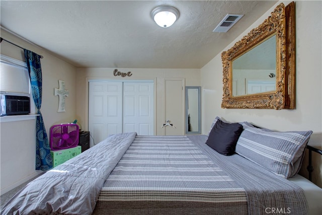 bedroom featuring a textured ceiling, cooling unit, and a closet