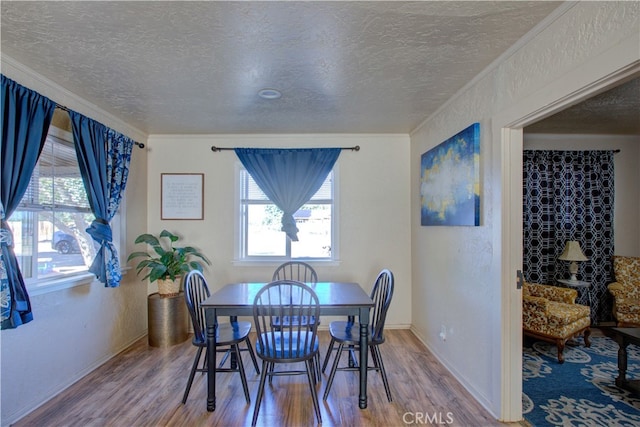 dining room featuring a textured ceiling, crown molding, and hardwood / wood-style floors