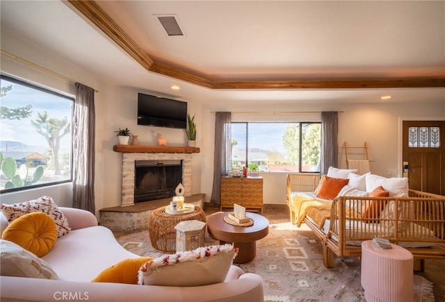 living room featuring a healthy amount of sunlight, a fireplace, and crown molding